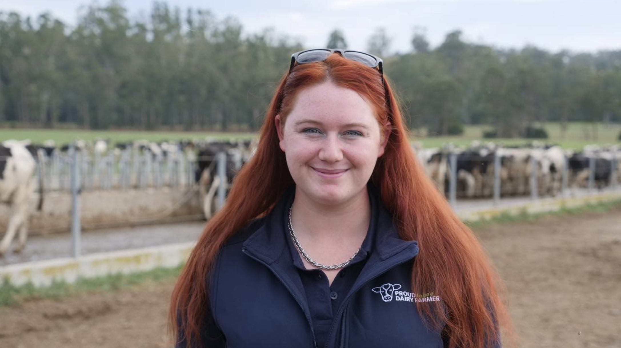 headshot of young female dairy farmer, Almira Dall, with dairy cows in the background